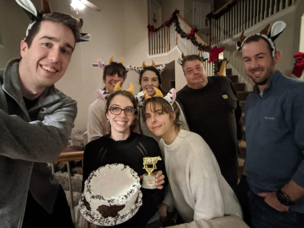Casey with people and a cake, all have on cow ears