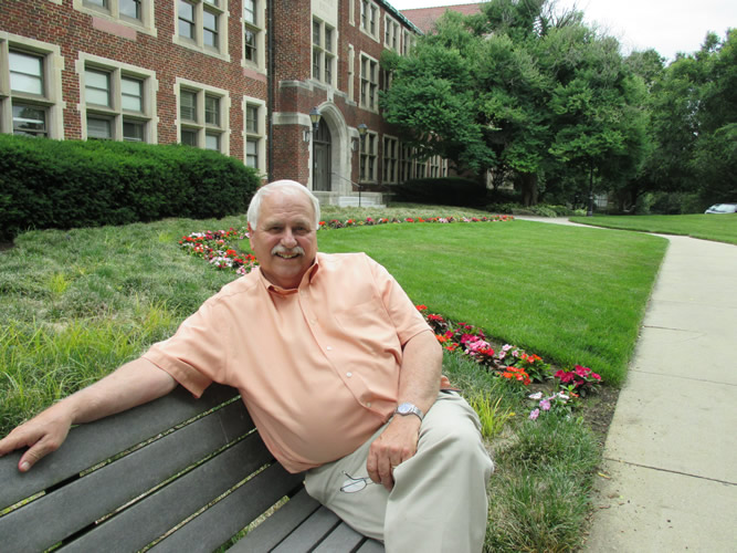 David Kirkpatrick sitting on a bench in front of Morgan Hall