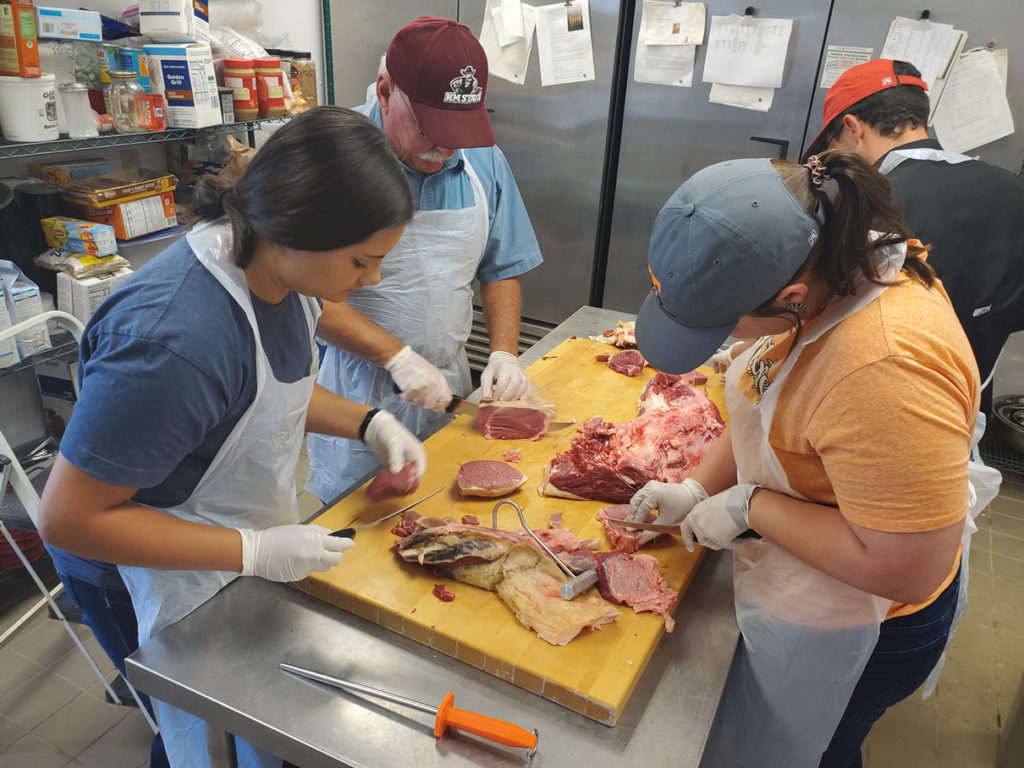 students working with meat cuts