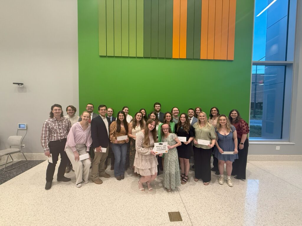 Group of students gathered in front of a green wall for a picture