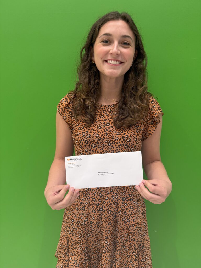 Female student standing in front of green wall posing for a picture