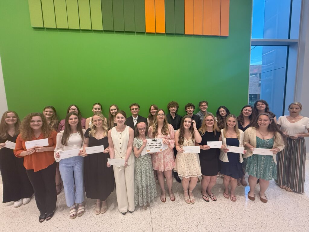 Students gathered for a picture in front of a green wall