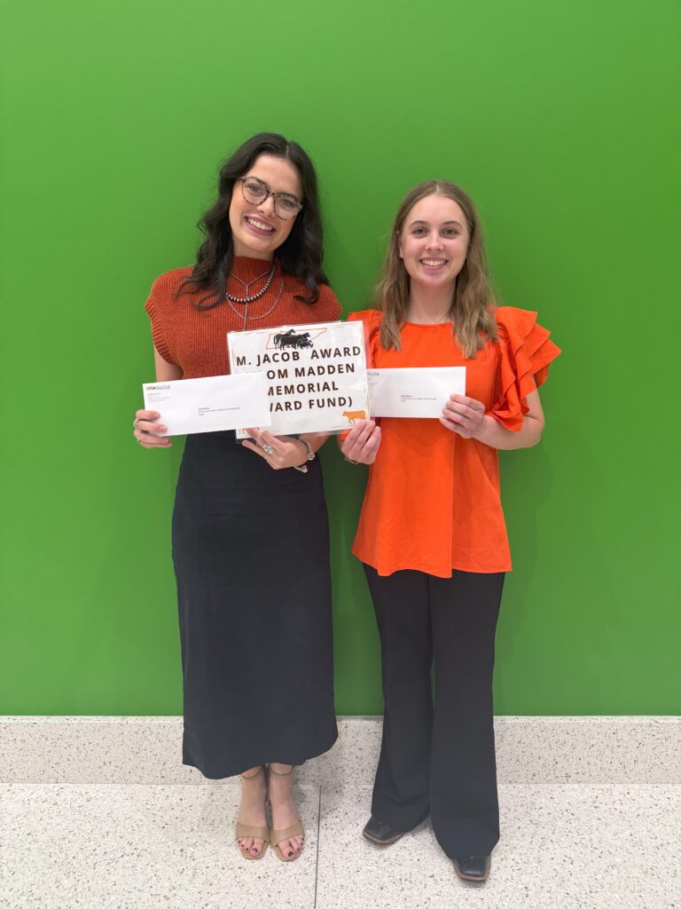 Two students gathered together in front of a green wall