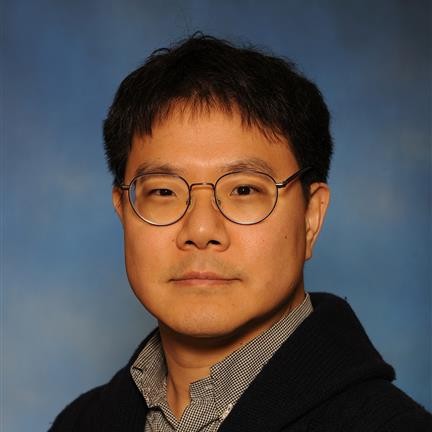 Headshot of Dr. Sim. He is wearing glasses and has short black hair. The background is blue. 